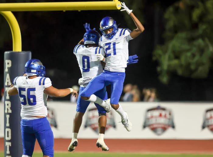 Zander Benitez (56), Skylar Lendsey (0) and Sean Embree (21) celebrate a touchdown in Friday's 34-14 win at Liberty. Photo: Joe Bergman